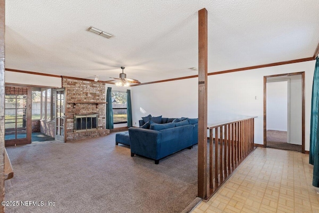 living room featuring ceiling fan, crown molding, a fireplace, and a textured ceiling