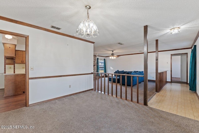 carpeted spare room with crown molding, a textured ceiling, and a notable chandelier