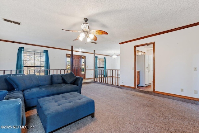 living room featuring ceiling fan, light colored carpet, ornamental molding, and a textured ceiling