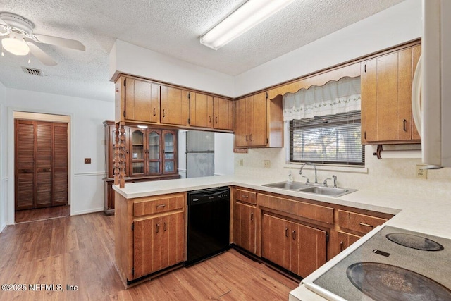 kitchen with black dishwasher, sink, white range oven, kitchen peninsula, and light wood-type flooring