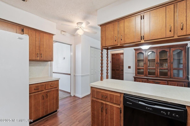 kitchen with wood-type flooring, a textured ceiling, white refrigerator, black dishwasher, and ceiling fan