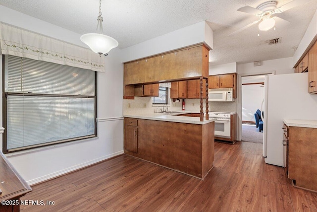 kitchen featuring hanging light fixtures, sink, dark wood-type flooring, and white appliances