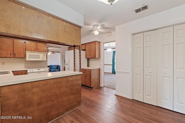 kitchen featuring ceiling fan, dark wood-type flooring, a textured ceiling, and white appliances