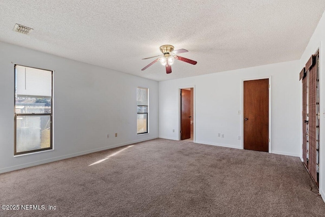 unfurnished bedroom featuring multiple windows, a textured ceiling, and carpet