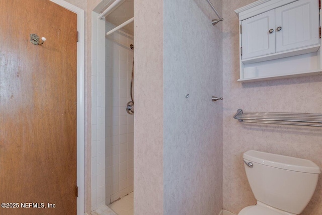 bathroom with a tile shower and toilet