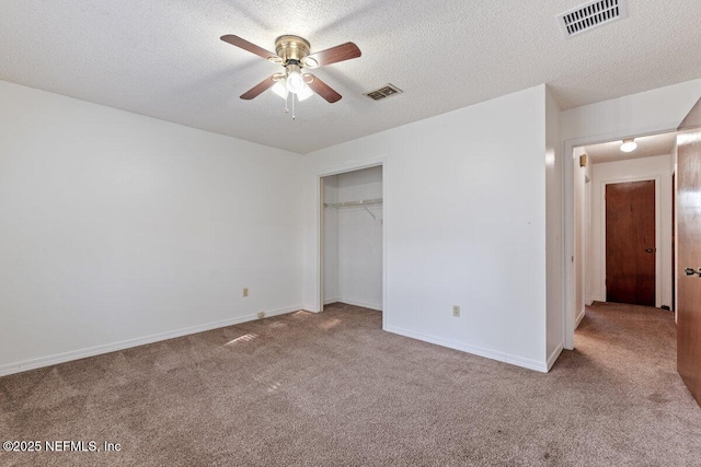 unfurnished bedroom featuring ceiling fan, light carpet, a textured ceiling, and a closet