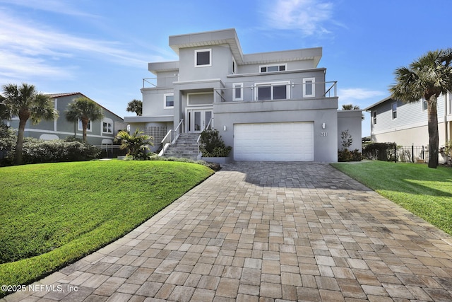 view of front of property featuring a garage, a balcony, and a front lawn