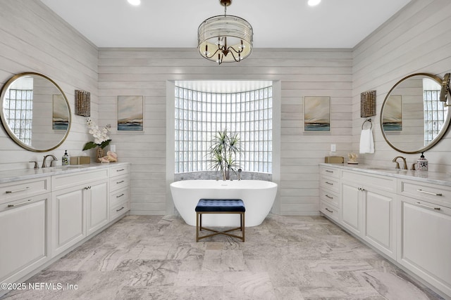 bathroom with vanity, a bath, and an inviting chandelier