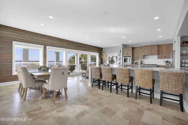 kitchen with stainless steel oven, wooden walls, and a kitchen breakfast bar