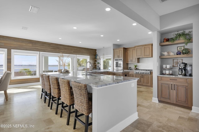 kitchen with a spacious island, stainless steel gas stovetop, a breakfast bar, and light stone counters