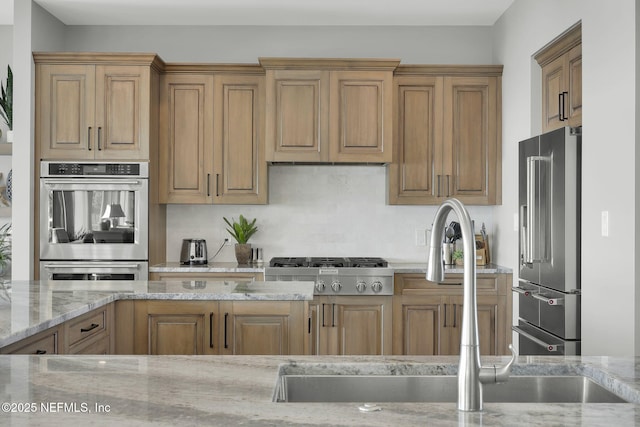 kitchen featuring light stone counters, sink, and stainless steel appliances