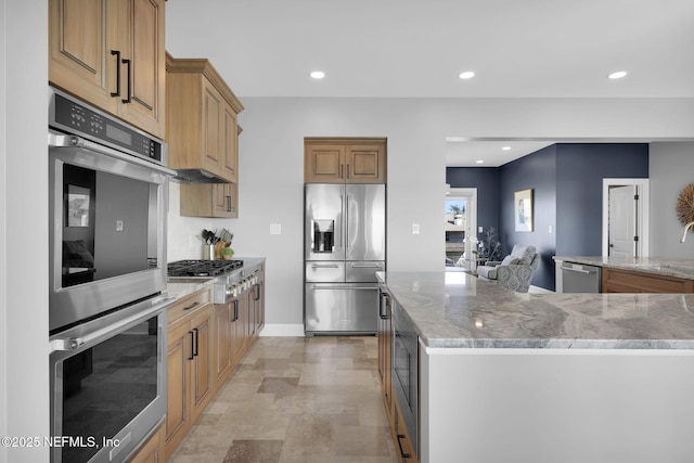 kitchen with light stone countertops, stainless steel appliances, sink, and a center island