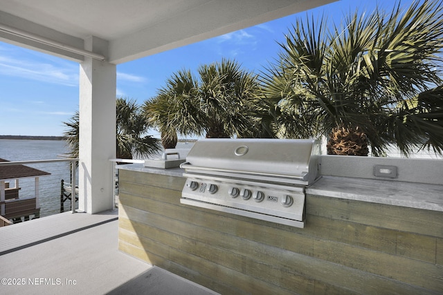 view of patio / terrace with a water view, a grill, and exterior kitchen