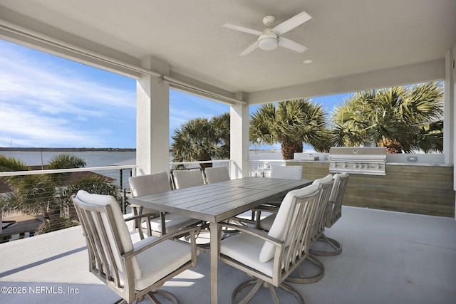 view of patio with area for grilling, exterior kitchen, ceiling fan, and a water view