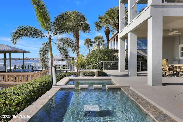 view of swimming pool featuring an in ground hot tub, a water view, ceiling fan, and a patio area