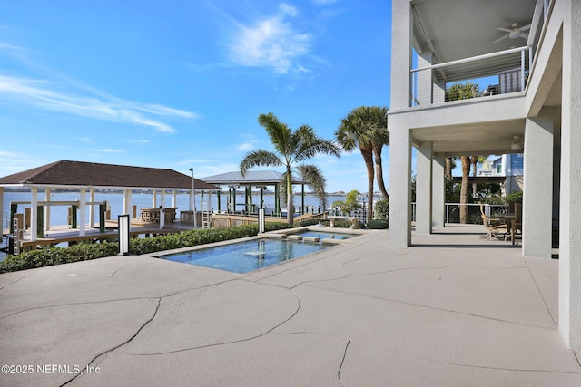 view of pool featuring ceiling fan, a gazebo, a water view, a patio area, and an in ground hot tub