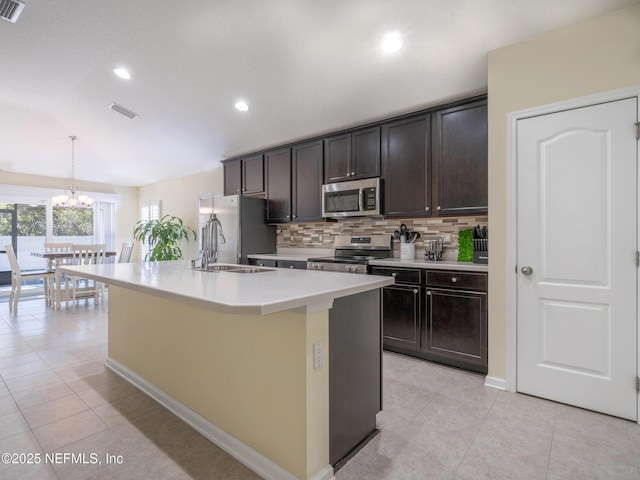 kitchen with sink, dark brown cabinets, stainless steel appliances, a center island with sink, and decorative light fixtures