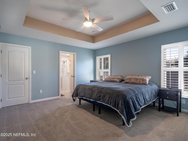 carpeted bedroom featuring ensuite bathroom, ceiling fan, a textured ceiling, and a tray ceiling