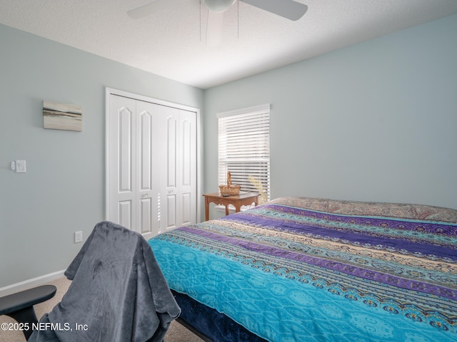 carpeted bedroom with a textured ceiling, ceiling fan, and a closet