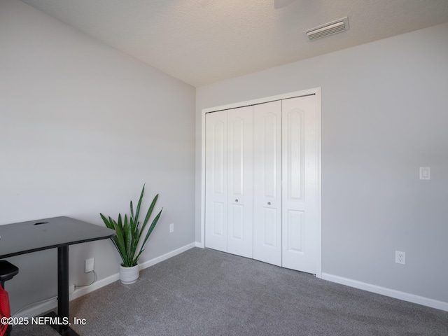 unfurnished office featuring dark carpet and a textured ceiling