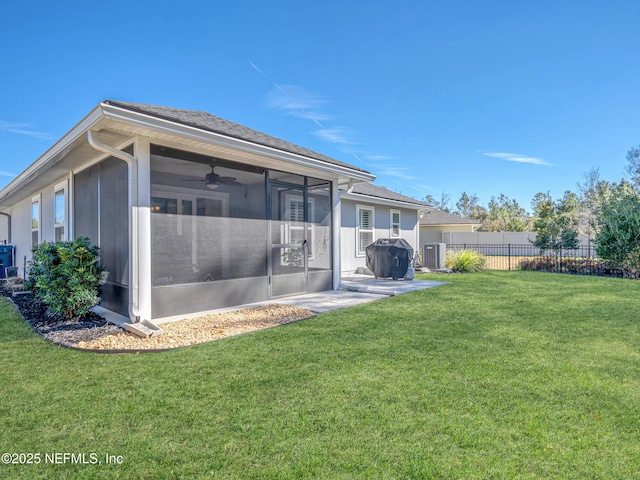 rear view of property featuring cooling unit, a lawn, a sunroom, and ceiling fan