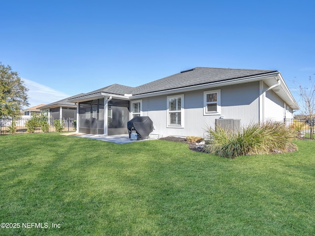 rear view of property with a sunroom, a patio area, central air condition unit, and a lawn