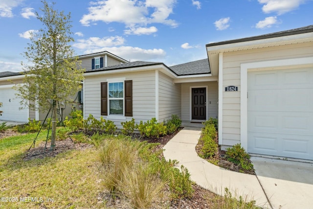 doorway to property featuring a garage and a lawn