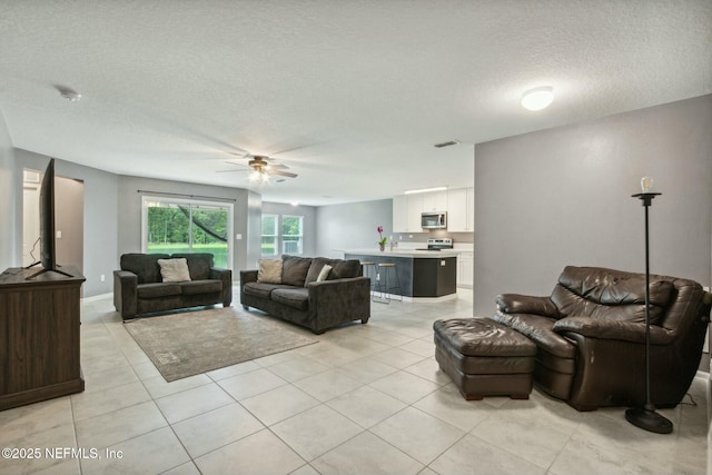 living room featuring light tile patterned floors, a textured ceiling, and ceiling fan