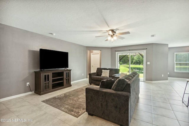 tiled living room with ceiling fan, plenty of natural light, and a textured ceiling