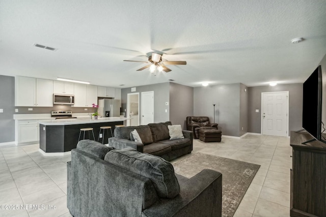 tiled living room featuring a textured ceiling and ceiling fan