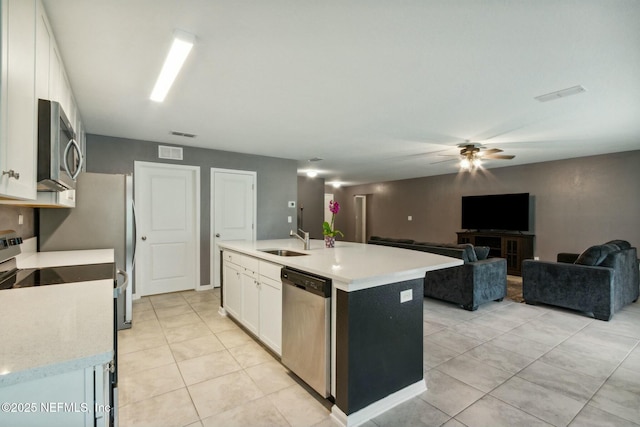 kitchen with appliances with stainless steel finishes, white cabinetry, sink, a kitchen island with sink, and light tile patterned floors