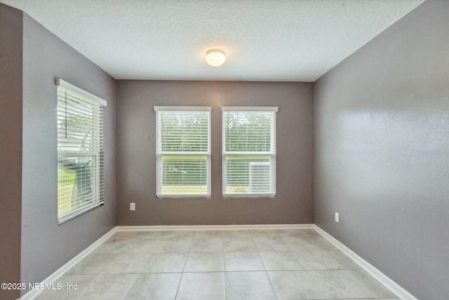 spare room with light tile patterned floors and a textured ceiling