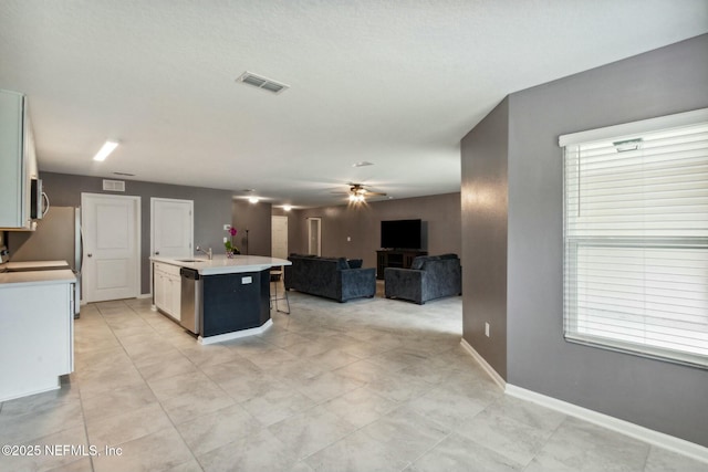 kitchen featuring sink, white cabinets, ceiling fan, stainless steel appliances, and a center island with sink