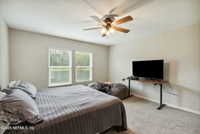 bedroom with ceiling fan, light colored carpet, and a textured ceiling