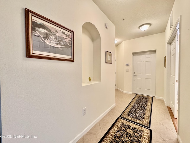 hallway featuring light tile patterned floors and a textured ceiling