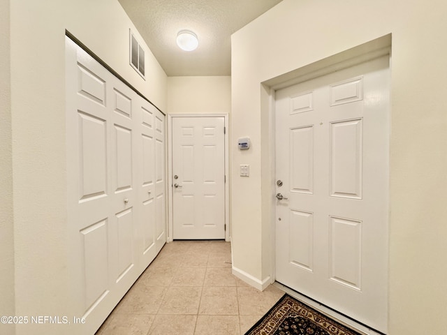 entryway featuring a textured ceiling and light tile patterned flooring