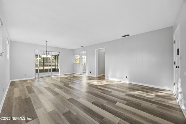 unfurnished living room with wood-type flooring and a chandelier