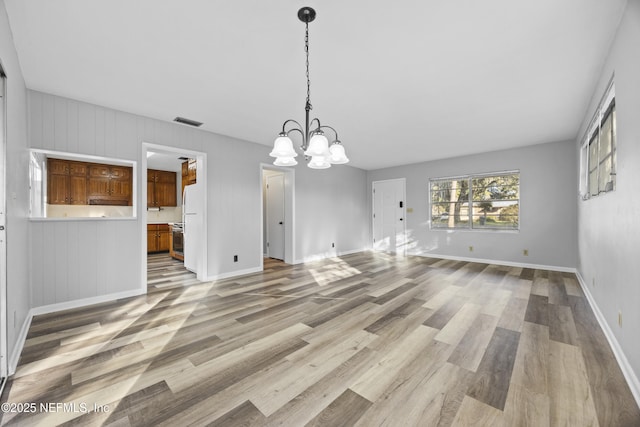 unfurnished dining area featuring a chandelier and light hardwood / wood-style flooring