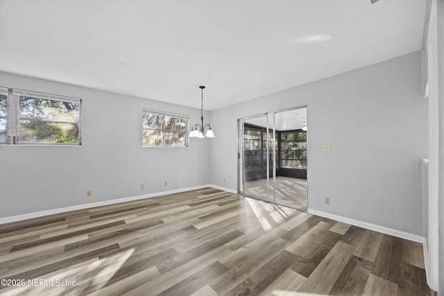 unfurnished dining area with an inviting chandelier and hardwood / wood-style floors