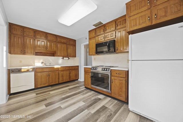 kitchen featuring light wood-type flooring, sink, and white appliances