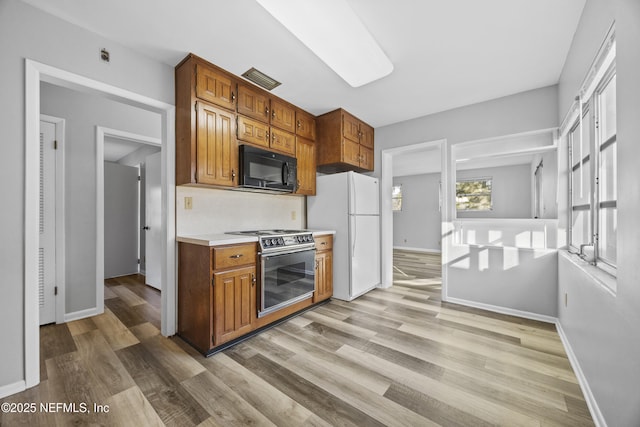 kitchen featuring light wood-type flooring, stainless steel range oven, and white refrigerator