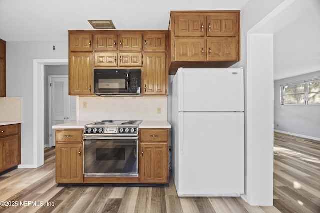 kitchen with electric range oven, light wood-type flooring, and white refrigerator