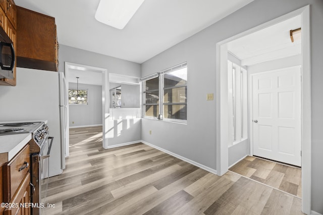 kitchen with a notable chandelier, light hardwood / wood-style flooring, and electric range