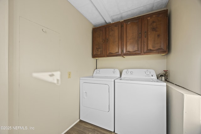 clothes washing area featuring dark hardwood / wood-style flooring, cabinets, and washing machine and clothes dryer