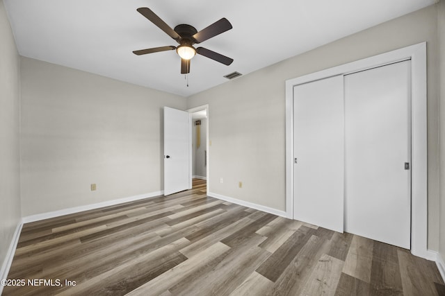 unfurnished bedroom with ceiling fan, hardwood / wood-style floors, and a closet