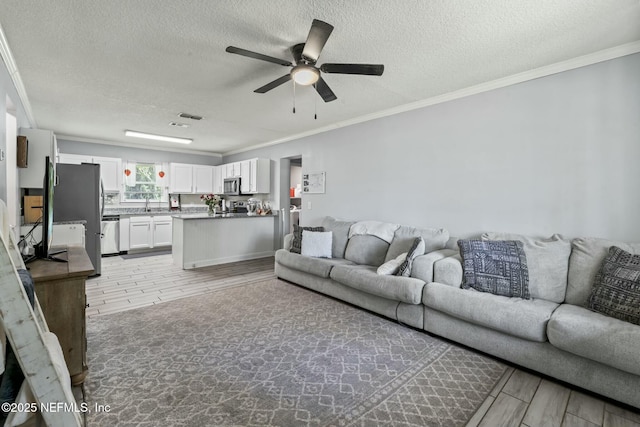 living room with crown molding, ceiling fan, light hardwood / wood-style floors, and a textured ceiling