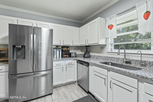 kitchen featuring white cabinetry, ornamental molding, appliances with stainless steel finishes, and sink