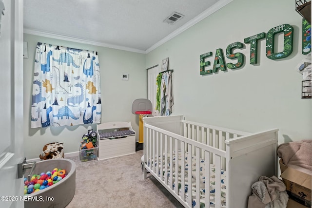 bedroom with carpet floors, a crib, ornamental molding, and a textured ceiling