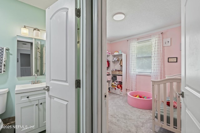 bathroom with ornamental molding, vanity, toilet, and a textured ceiling