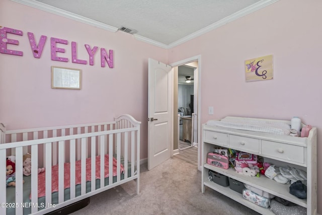 carpeted bedroom featuring ornamental molding, a textured ceiling, and a crib